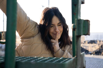 cheerful and friendly young brunette woman making expressive faces on the gangway of a freight...
