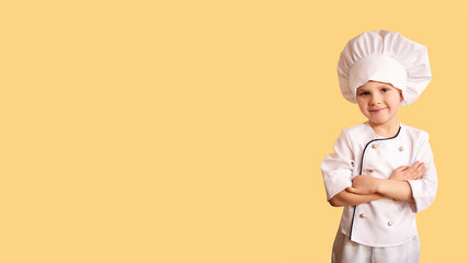 Smiling cheerful child in white chef uniform on the yellow background.Large banner with negative space.