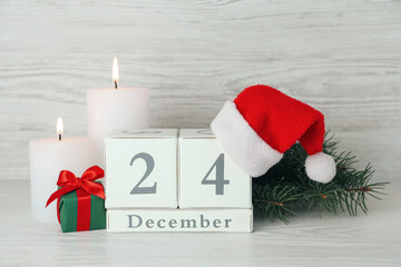 Obraz na płótnie Canvas Christmas Eve - December 24. Block calendar and festive decor on white wooden table