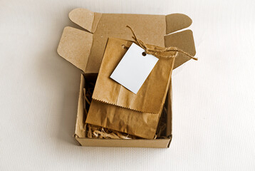 Kraft paper bags in a box on a light background with a blank label. Packaging template mock up. 