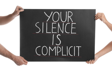 Man and woman holding sign with phrase Your Silence Is Complicit on white background, closeup....