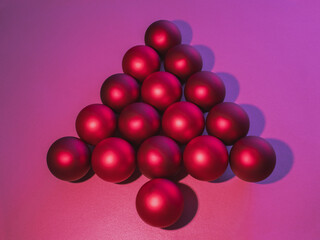 Red baubles like christmas tree or arrow on pink background, minimal aesthetic, creative layout arrangement. Biliard start position.