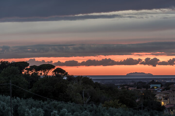 Mittelalterliche Stadt n der Dämmerung mit Olivenhain und Weinberg vor Mittelmeer, Wolken  bei Sonneuntzergang 
