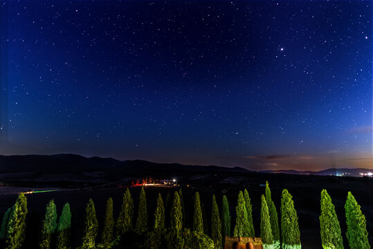 Toskana in der Nacht mit beleuchteten Zypressen, Hügeln und Sternenhimmel