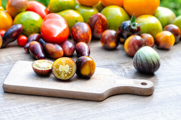 table with a cutting board with sliced tomatoes with different colored tomatoes in the background