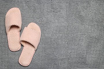Slippers on soft grey bath mat, flat lay. Space for text