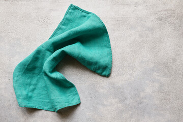 Green folded linen napkin on gray concrete table with copy space, top view