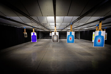 professional Indoor target shooting range looking down range at targets. Assorted targets have...