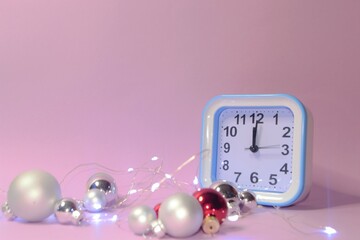 Clock and Christmas silver balls with red candles. Blurred lights in the background. New Year