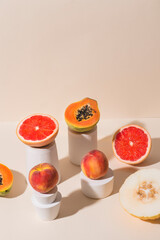 Fruits (papaya, melon, grapefruit, peaches and apricots) in calming coral colors in white stands...