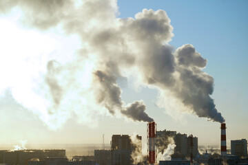 Fototapeta na wymiar Smoke from city chimneys covers the blue sky against the backdrop of the shining sun