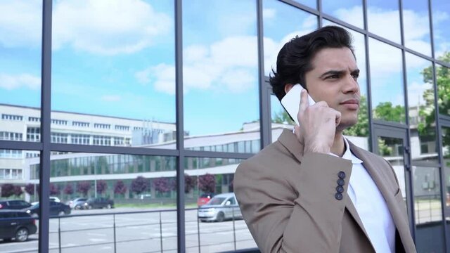 slow motion of businessman talking on smartphone near modern building