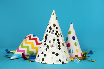 Colorful party hats and festive items on light blue background