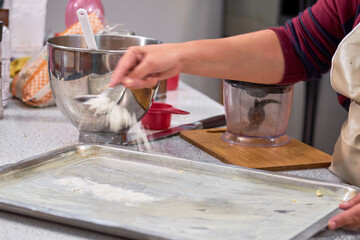 Woman puts flour on steel tray for cooking.