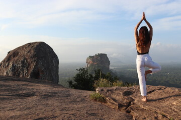 Woman does yoga on a rock formation somewhere in Sri Lanka
