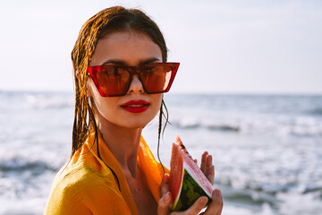 woman on the beach near the ocean eating watermelon