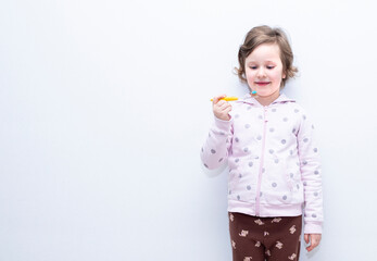 The child smiles and brushes his teeth with a toothbrush. Caucasian girl 6 years old, holding a toothbrush in her hands.