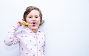 A child, a Caucasian girl, 6 years old, thoroughly brushes her teeth with a toothbrush and toothpaste. Hygiene of teeth and oral cavity.