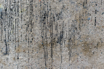 Concrete wall with splashes of black paint. Roughness, stones.