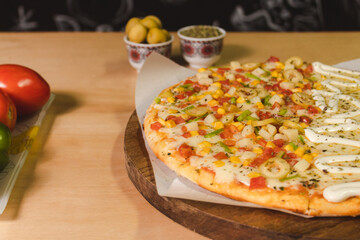 Acercami of a vegetable pizza with lots of mozzarella cheese on top of a wooden table.