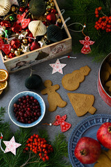 Festive background with Christmas cookies, cranberries, dried oranges, fruits, fir branches, Christmas toys.