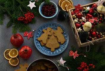 Festive background with Christmas cookies, cranberries, dried oranges, fruits, fir branches, Christmas toys.