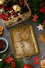 Beautiful festive cookies on a golden tray. Festive background with Christmas cookies, cranberries, dried oranges, fruits, fir branches, Christmas toys.