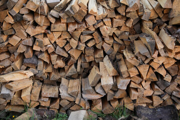 Stack of cut firewood on green grass outdoors