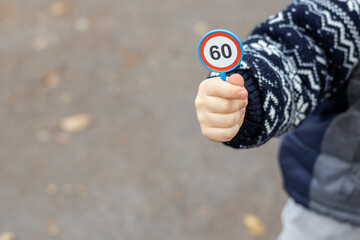 toy traffic signs in a kid boy hand. plastic road sign with speed limit of 60 km per hour,crosswalk...