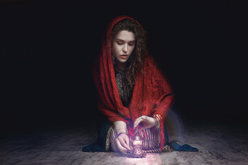 a girl in a dark room lights a candle