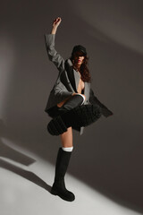 High fashion shot of a sexy young model woman with perfect body wearing a stylish blazer and high boots