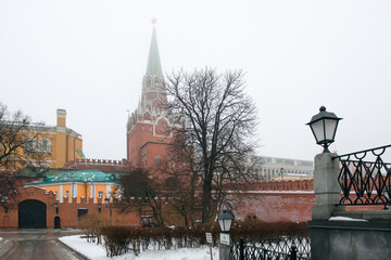 Moscow, Russia.  Alexander Garden (Aleksandrovsky Sad) and Troitskaya Tower of the Moscow Kremlin аt winter in fog. Misty winter morning in Moscow.