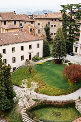 Green flowerbed with trees in the courtyard of an old house in Bergamo. Top view