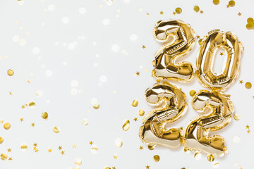 New year 2022 balloon celebration card. Gold foil helium balloon number 2022, party decoration, gold confetti stars on white background. Flat lay, merry christmas, happy holidays concept, top view