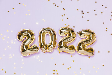 New year 2022 balloon celebration card. Gold foil balloon number 2022, party decoration, gold confetti on lavender background. Flat lay, merry christmas, happy holidays concept.