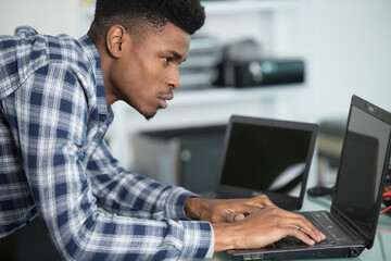 young male computer technician using laptop