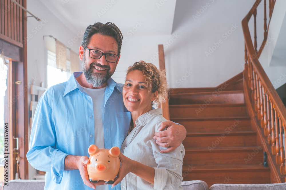 Wall mural portrait of happy caucasian couple holding piggy bank to save money to make their future dreams come