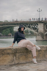 Caucasian girl sitting outdoors overlooking Isabel II bridge, Triana bridge.