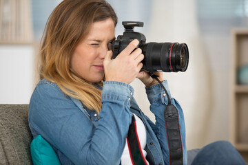 woman sat on the sofa focusing her camera lens