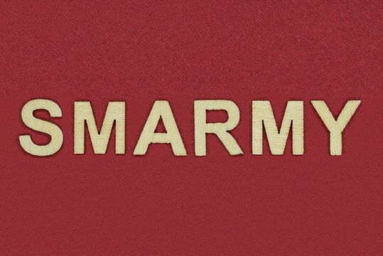 text the word smarmy from gray wooden small letters on an red table