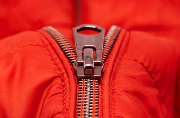 Close-up zipper on light red clothing, jacket. Zipper closure with lock.