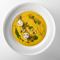 Pumpkin soup with pumpkin seeds on a white background
