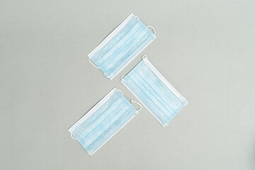 Medical blue surgical masks on grey background. Protect from the Covid 19 virus during the pandemic and keep yourself clean and maintain good hygiene. Flat lay pattern