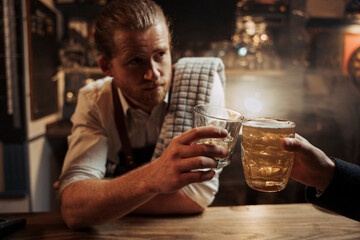caucasian male bartender enjoying drink with customer sitting at the bar 