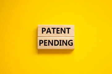 Time to patent pending symbol. Concept words Patent pending on wooden blocks on a beautiful yellow background. Business and patent pending concept. Copy space.