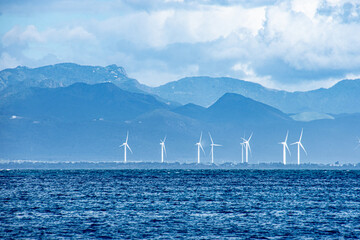 Dramatic view of white wind turbines on a background of blue mountains seen from the blue wave...