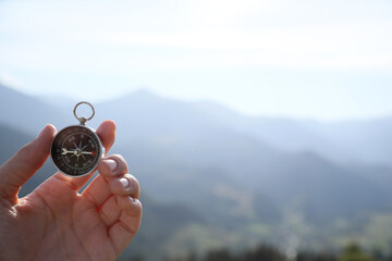 Woman using compass during journey in mountains, closeup