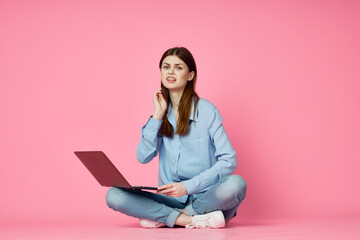 Naklejka premium woman with laptop sitting on floor technology internet shopping pink background