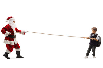 Full length profile shot of a schoolboy and santa claus pulling a rope