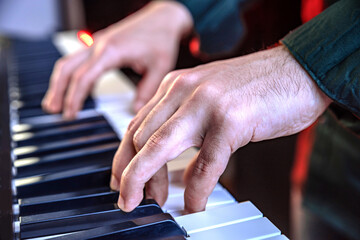 Male hands playing electric Digital Piano. Musician man with black guitar at a rock concert